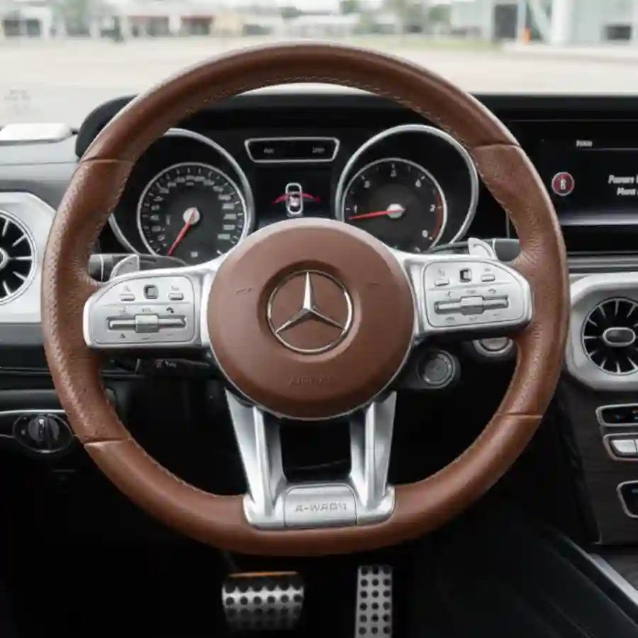 Mercedes G-Wagon G550 interior view featuring a brown leather steering wheel, luxury dashboard controls, and gauges, emphasizing customization options for the limousine configurator by Big Limos.