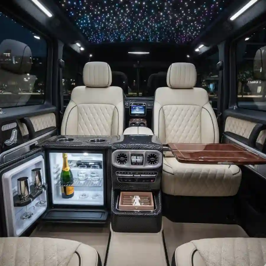 Luxury interior of a Mercedes G-Wagon G63 limousine featuring plush beige seating, a minibar with champagne, and a starry ceiling, highlighting customization options for a premium vehicle experience.